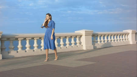 Beautiful young woman walking and talking with cell phone.