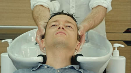 Professional hairdresser washing hair to her handsome client.の写真素材