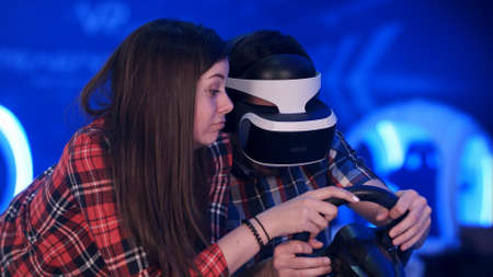 Bored girl trying to distract her boyfriend from playing virtual reality racing game
