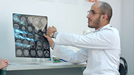 Smiling doctor showing brain computed tomography x-ray image to his patientsの写真素材