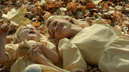 Mother and daughter in autumn yellow park.の写真素材