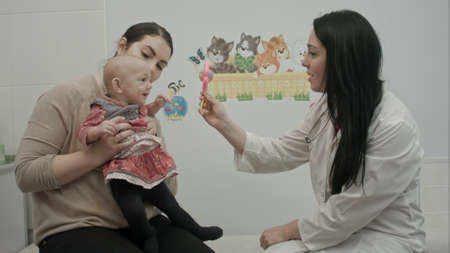 Cute baby being examine by pediatrician with toyの写真素材