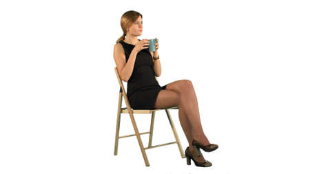 A young attractive woman with a cup of coffee or tea on laptop on white background isolatedの写真素材