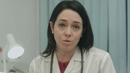 Serious female doctor talking about a illness and result at modern hospital indoorsの写真素材