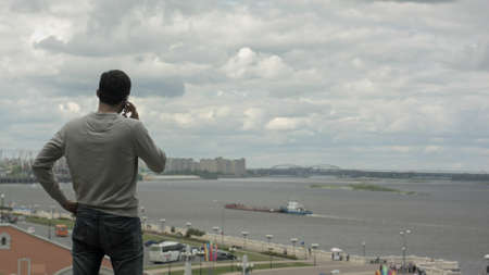 Businessman traveling. Talking on his mobile phone near riverの写真素材
