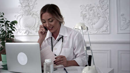 Female medical doctor talking on the phone and looking documents.の写真素材
