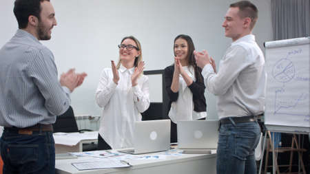 Cheerful office people applauding and shaking their hands after great work