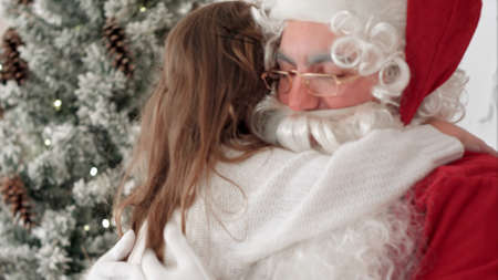 Pretty little girl presenting Santa Claus with Christmas giftの写真素材