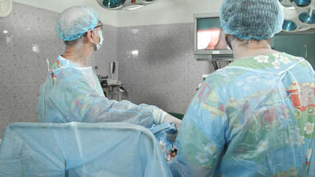 Surgeons follow the laparoscopic surgery, looking at screenの写真素材