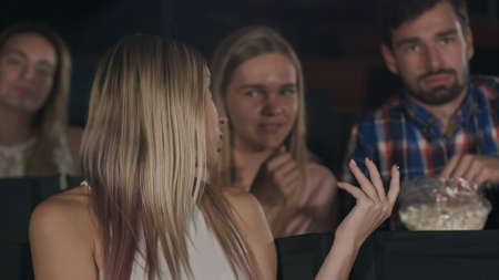 Rude man and woman talking disturbing woman at the near seats in the cinemaの写真素材