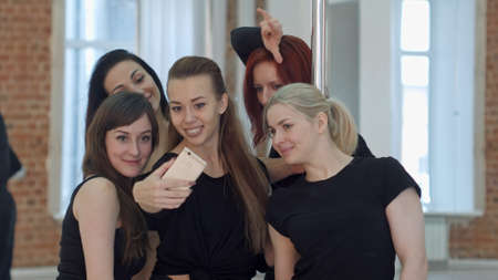 Group of young women taking a selfie during a break on a pole fitness classの写真素材