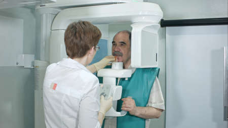 Young woman dentist peparing patient for analyzes a dental panoramic x-ray film in clinicの写真素材