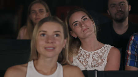 Group of friends watching a movie at the cinema theater and applauding at the end