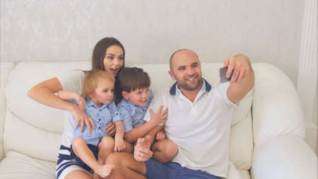 Smiling family taking funny selfies sitting on the sofaの写真素材