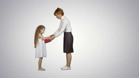 Beautiful young mom giving a present to her charming little girl on white backgroundの写真素材