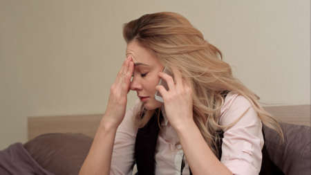 Portrait of unhappy young woman making annoyed phone call at homeの写真素材