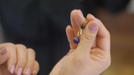 Female hand with bracelet on it holding designed earringの写真素材