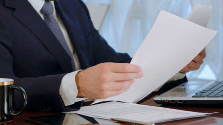Businessman signing documents with a cup of coffee on the tableの写真素材