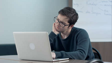 Pensive student with laptop studying in the university libraryの写真素材