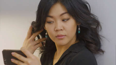Young asian woman takes selfie in new designed earrings using smartphoneの写真素材