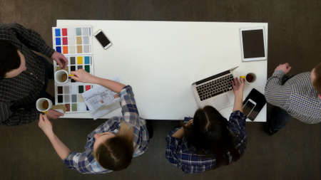 Four architects clearing the desk after a long working dayの写真素材