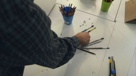Man artist sorting out paintbrushes in jarsの写真素材