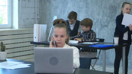 The kids discuss project in office, while one business girl talking on phoneの写真素材