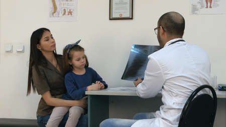 Doctor explaining chest xray image to mother holding little daughter in her armsの写真素材