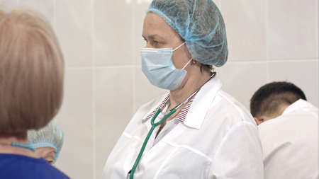 Serious female doctor in mask standing in a surgical roomの写真素材
