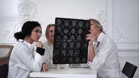 Three women doctors working with x-ray photo in the office.の写真素材
