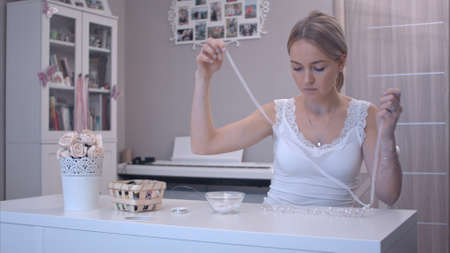 Young woman attaching ribbon to handmade jewelryの写真素材