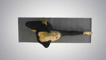Portrait of a young woman stretching body, looking at camera above on white backgroundの写真素材