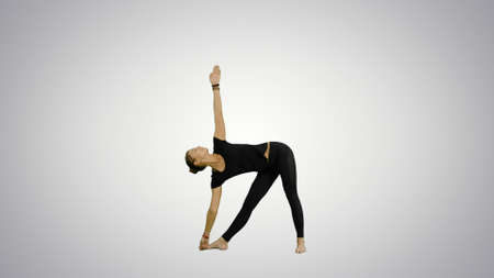 Sporty beautiful smiling young woman standing in Utthita Trikonasana, extended Triangle Pose on white backgroundの写真素材