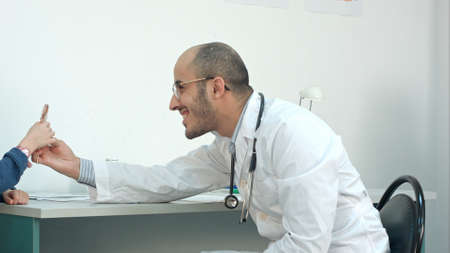 Smiling doctor giving little patient a lollipop after the examの写真素材