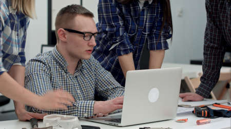 Serious manager in glasses looking at computer and talking to his teamの写真素材