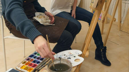 Art teacher and her apprentice working on a watercolor pictureの写真素材