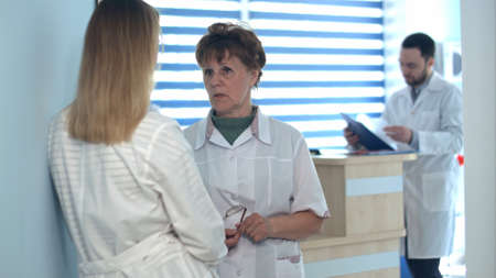 Two nurses talking near reception deskの写真素材
