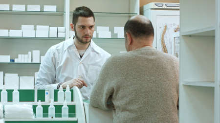 Senior man coming to drugstore to buy tablets or pillsの写真素材