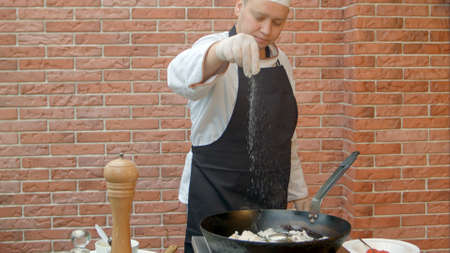 Chef putting salt and pepper to the pan for cooking seafoodの写真素材