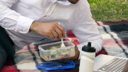 businessman wsiting on green grass, eating lunch,の写真素材