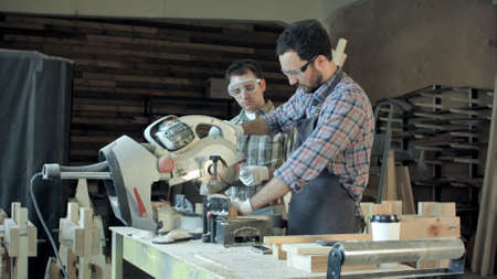 Two carpenters works on woodworking machine in workshop.の写真素材