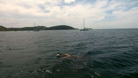 Copter aerial view, fly over the yachts moored in a bay and man swimming with maskの写真素材