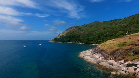 Copter aerial view of yacht moored in a bay near beach, where people are swimming and having sunbathの写真素材