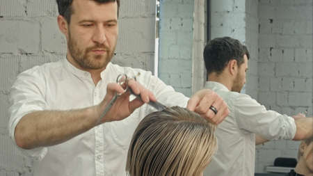 Hairdresser cutting hair in salon closeupの写真素材