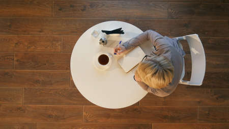 Young attractive business woman makes notes in a notebook sitting in cafeの写真素材