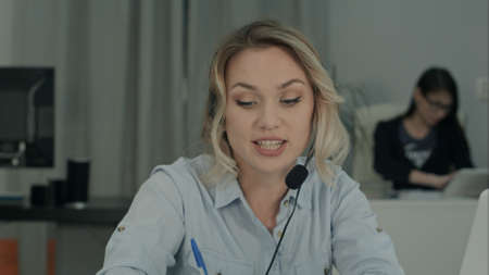 Young female manager in headset having business discussion via laptopの写真素材