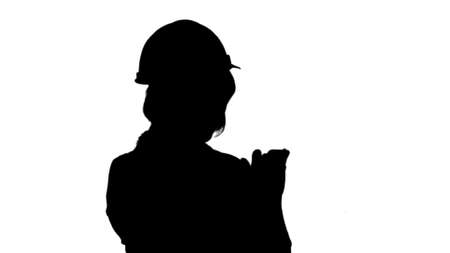 Silhouette Female architect with orange helmet using smartphone track matteの写真素材