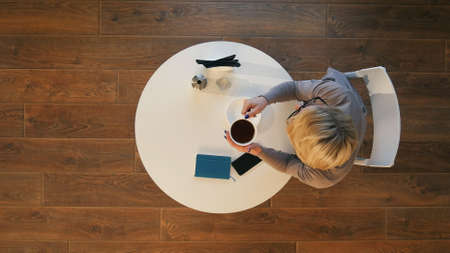 Pleasant woman drinking coffee in cafe in the morningの写真素材