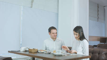Business partner giving money to female coworker in cafe and she counting itの写真素材