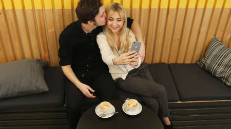 Young couple taking a photo of themselves in a cafeの写真素材